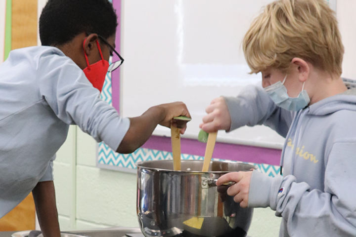 two boys mixing something in a mixing bowl